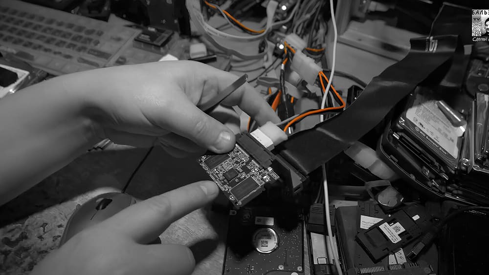 Мастер аккуратно подключает SSD-накопитель к компьютеру с помощью переходника для диагностики или ремонта.