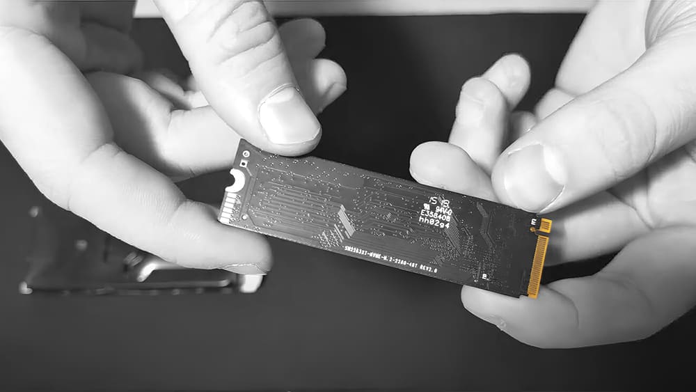Руки аккуратно держат SSD-накопитель M.2, готовый к диагностике или ремонту в сервисном центре.