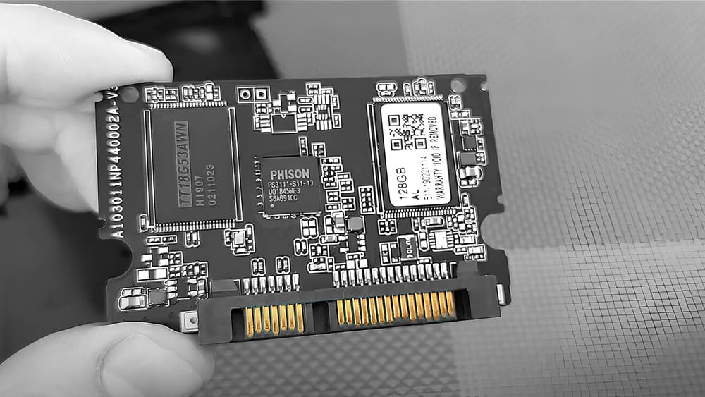 Специалист держит SSD-накопитель Phison с видимой платой и чипами, готовый к диагностике или ремонту.